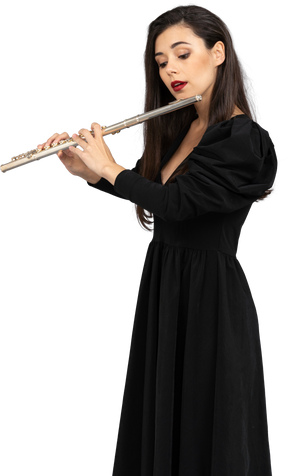 Three-quarter view of a serious young lady in black dress playing the flute