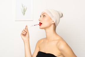 Молодая женщина засовывает шприц в рот
