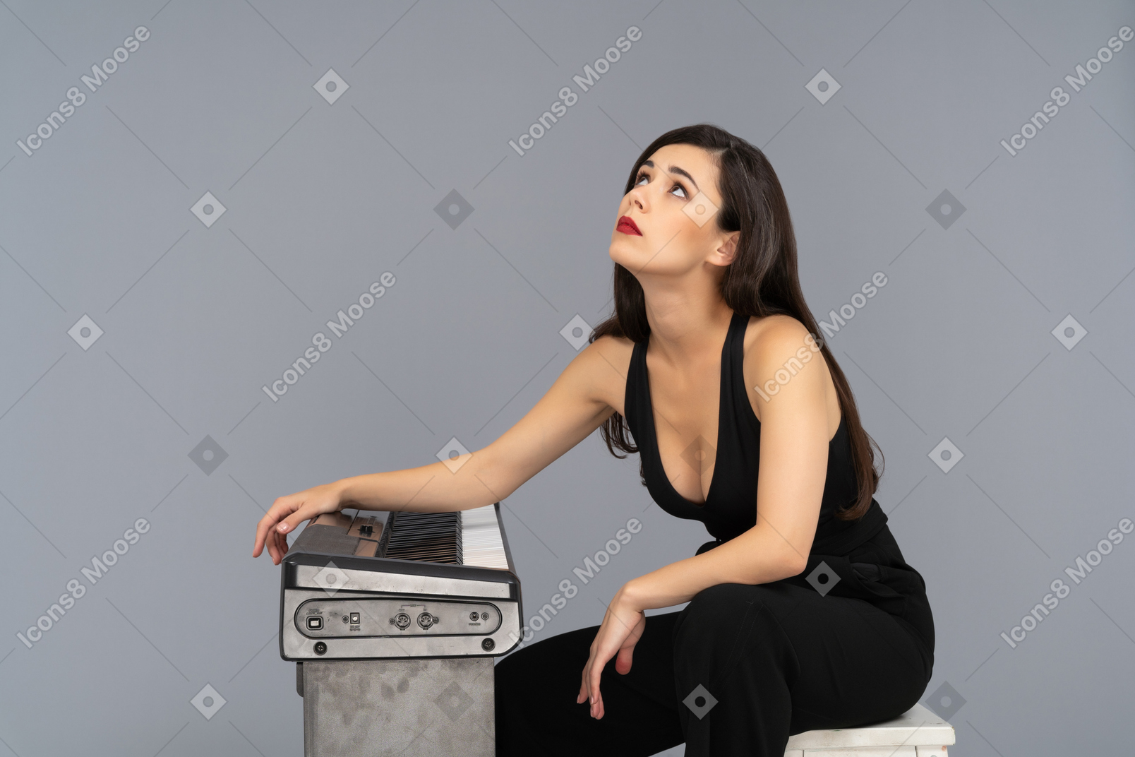 Серьезная молодая женщина теряется в мысли рядом с пианино