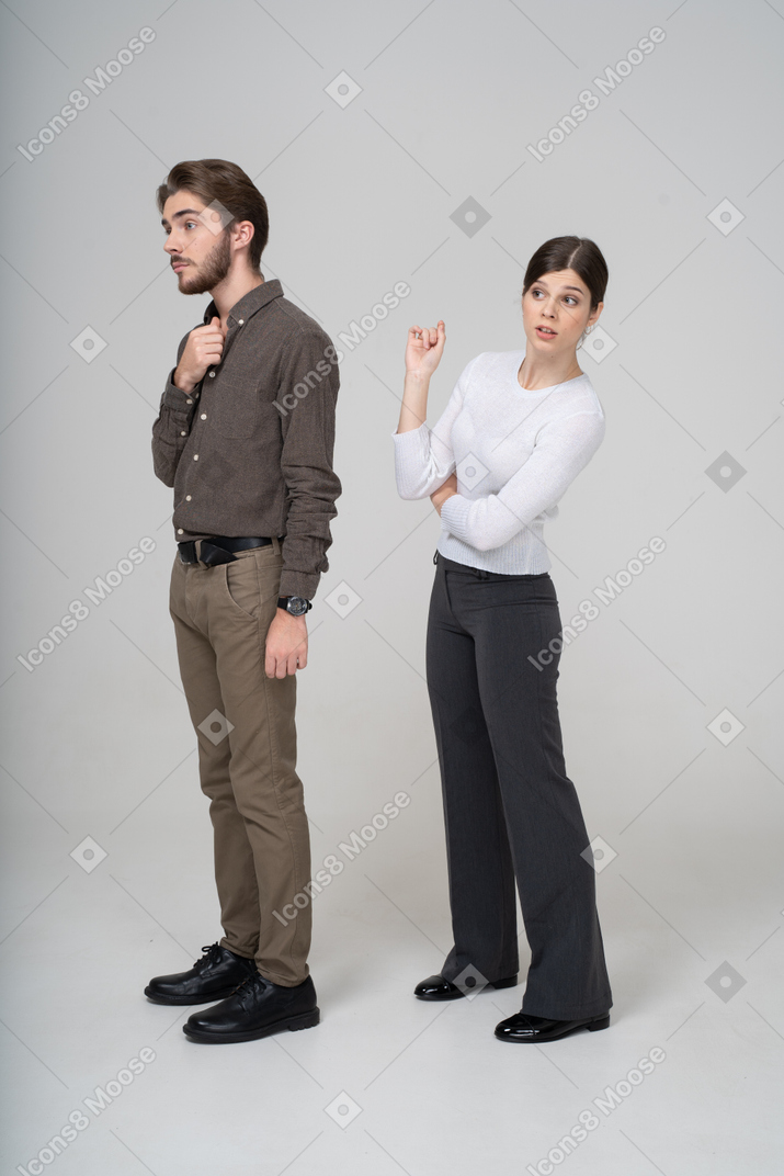 一对好奇的年轻夫妇，在办公室服装中的四分之三的视图