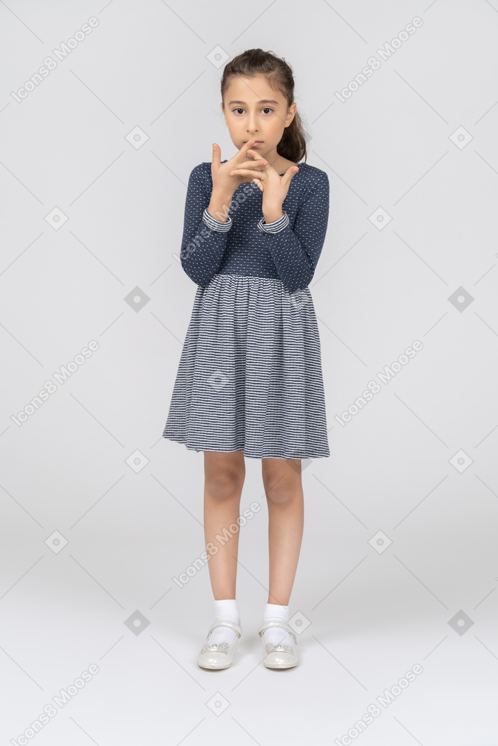 Vista frontal de uma garota olhando distraída com os dedos entrelaçados