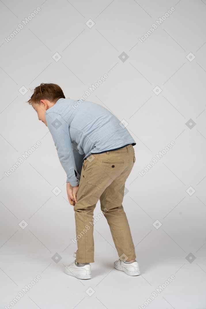 Back view of a boy bending down and touching knees