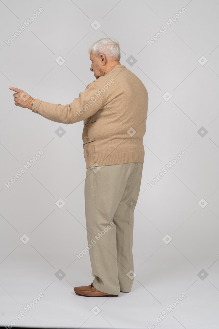指で指しているカジュアルな服装の老人の側面図
