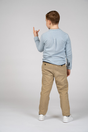 Rear view of a boy making rock gesture