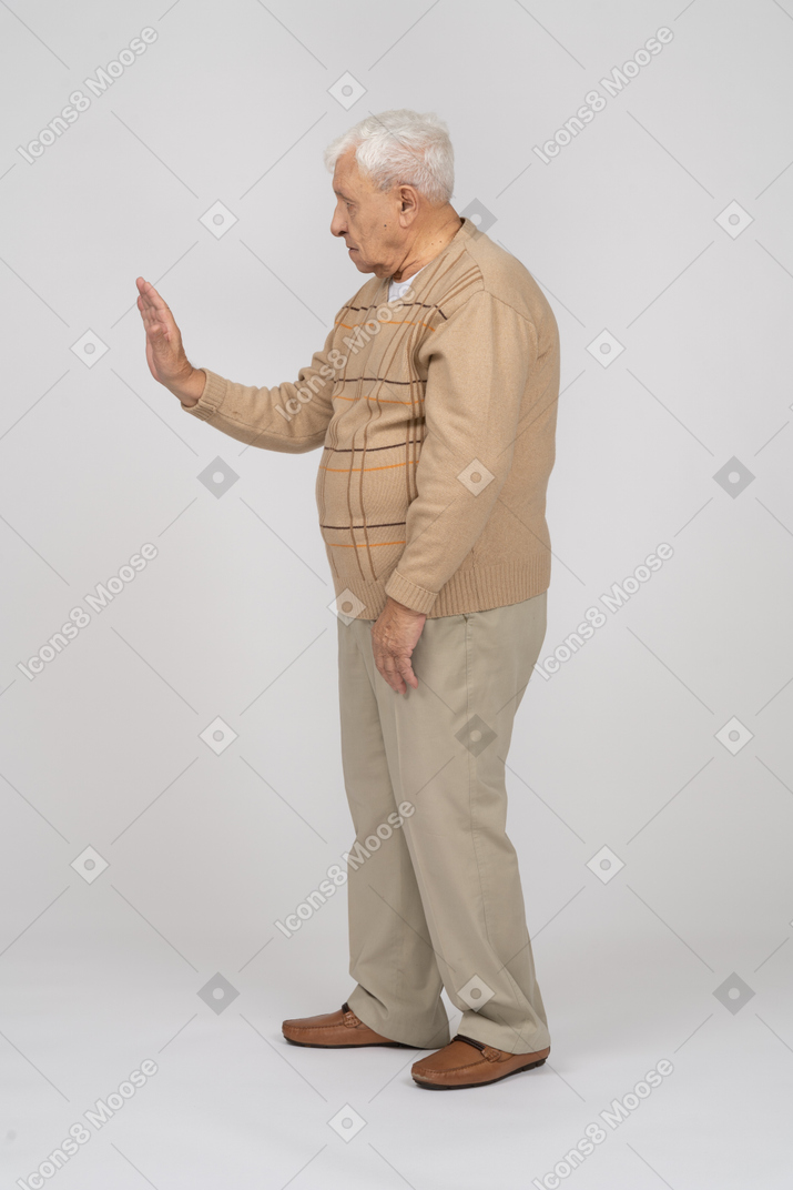 Vue latérale d'un vieil homme en vêtements décontractés montrant un geste d'arrêt