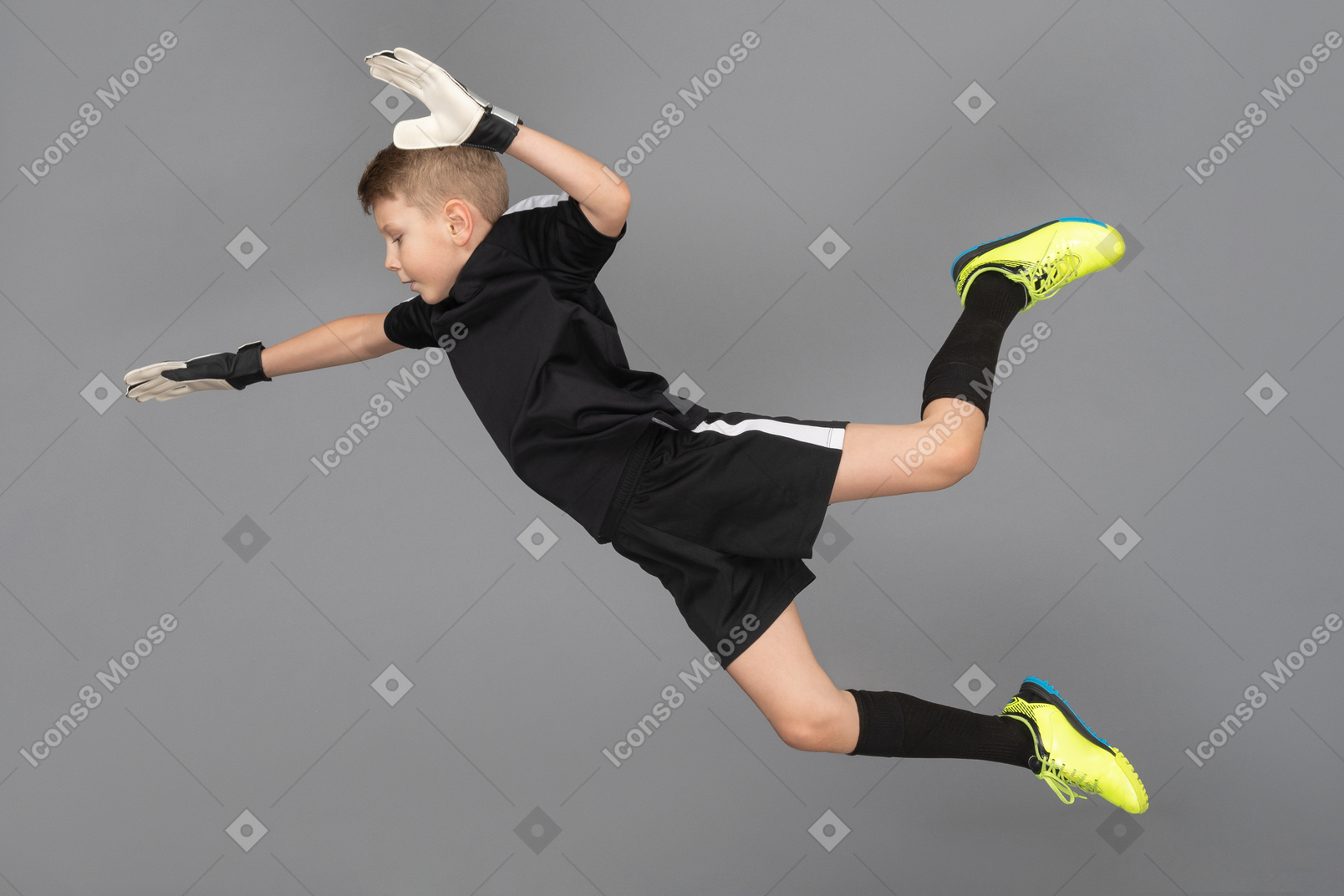 Vista lateral de un niño chico portero saltando y extendiendo las manos