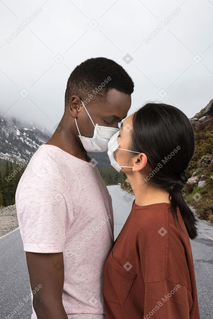 A man and a woman kissing each other through face masks