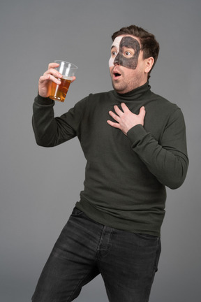 Three-quarter view of a surprised male football fan holding a beer