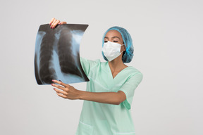 Woman doctor in face mask checking x-ray