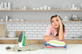 A woman sitting at a table with a stack of clothes in front of her