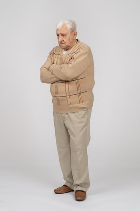 Vista lateral de un anciano con ropa informal de pie con los brazos cruzados