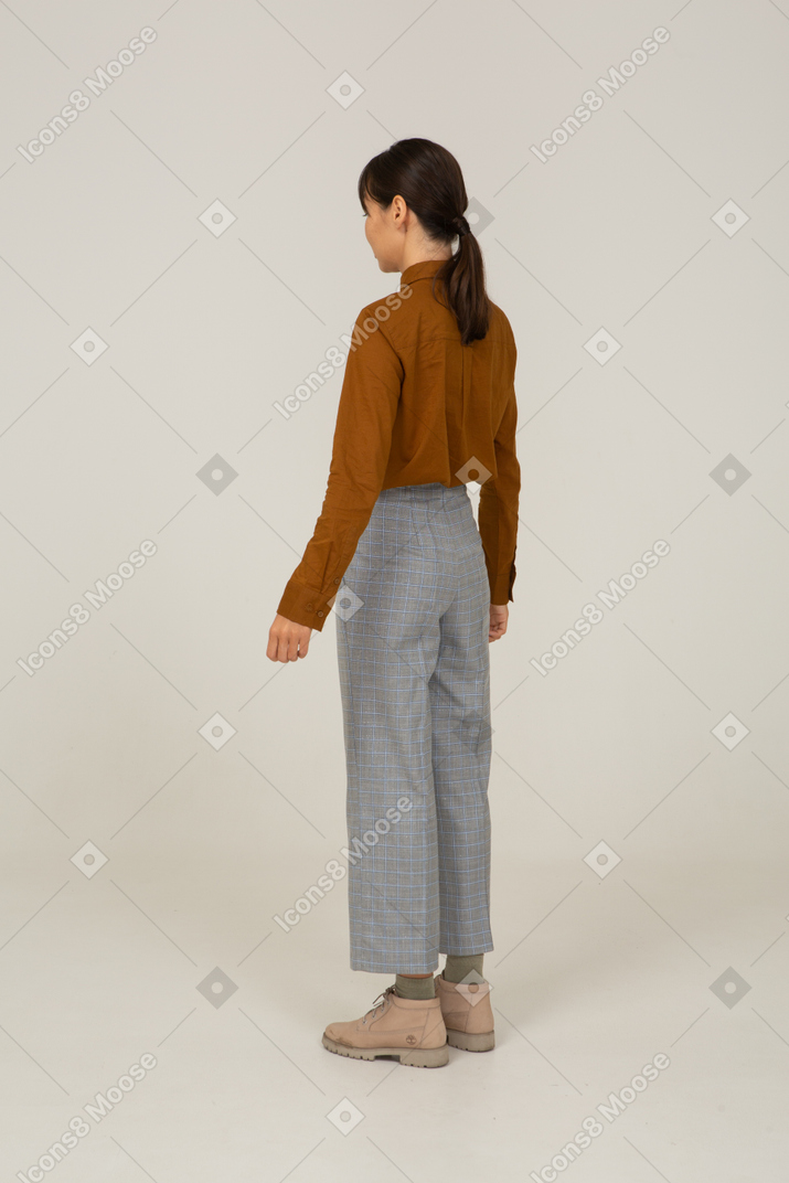 Vue de trois quarts arrière d'une jeune femme asiatique en culotte et chemisier immobile