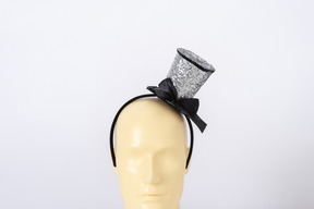 Small silver top hat with a bow on a mannequin head