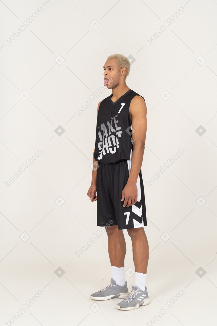 Vista de tres cuartos de un joven jugador de baloncesto masculino mostrando la lengua