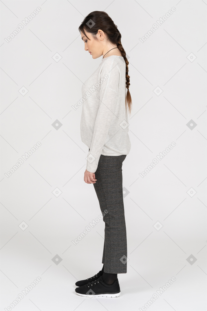 Mujer joven con larga trenza marrón de pie de perfil
