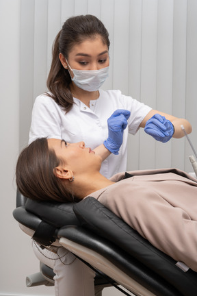 Un dentista femminile che dà un consiglio guardando la sua paziente di sesso femminile