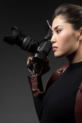 Giovane donna in possesso di una macchina fotografica e guardando lateralmente