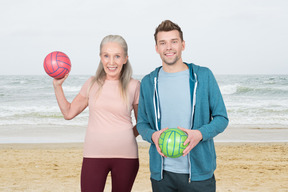A man and a woman holding volleyball balls