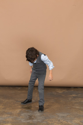 Vista frontal de un niño con traje gris mirando hacia abajo