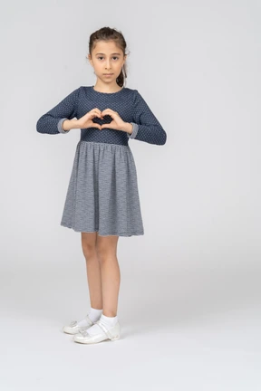 Three-quarter view of a girl turning and making heart with her hands