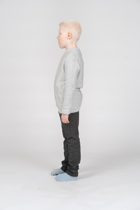 Side view of a kid boy in casual clothes looking down and opening mouth