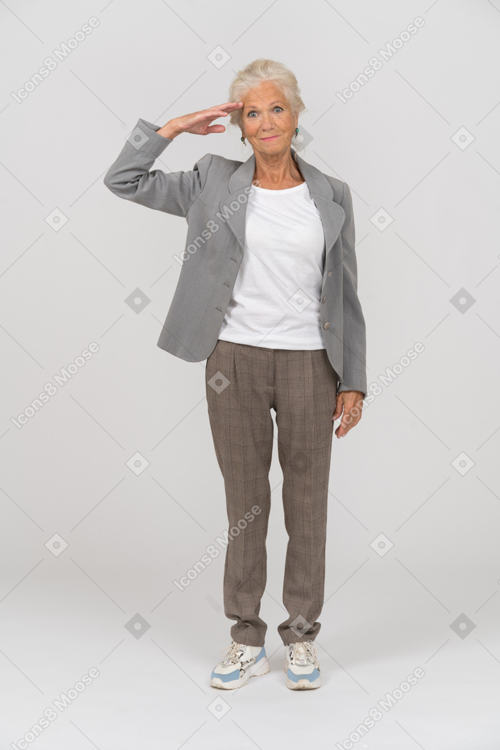 Vorderansicht einer alten dame im anzug, die mit der hand salutiert