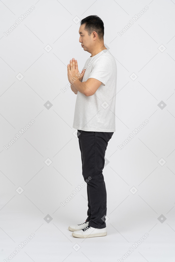 Side view of a man in casual clothes making praying gesture
