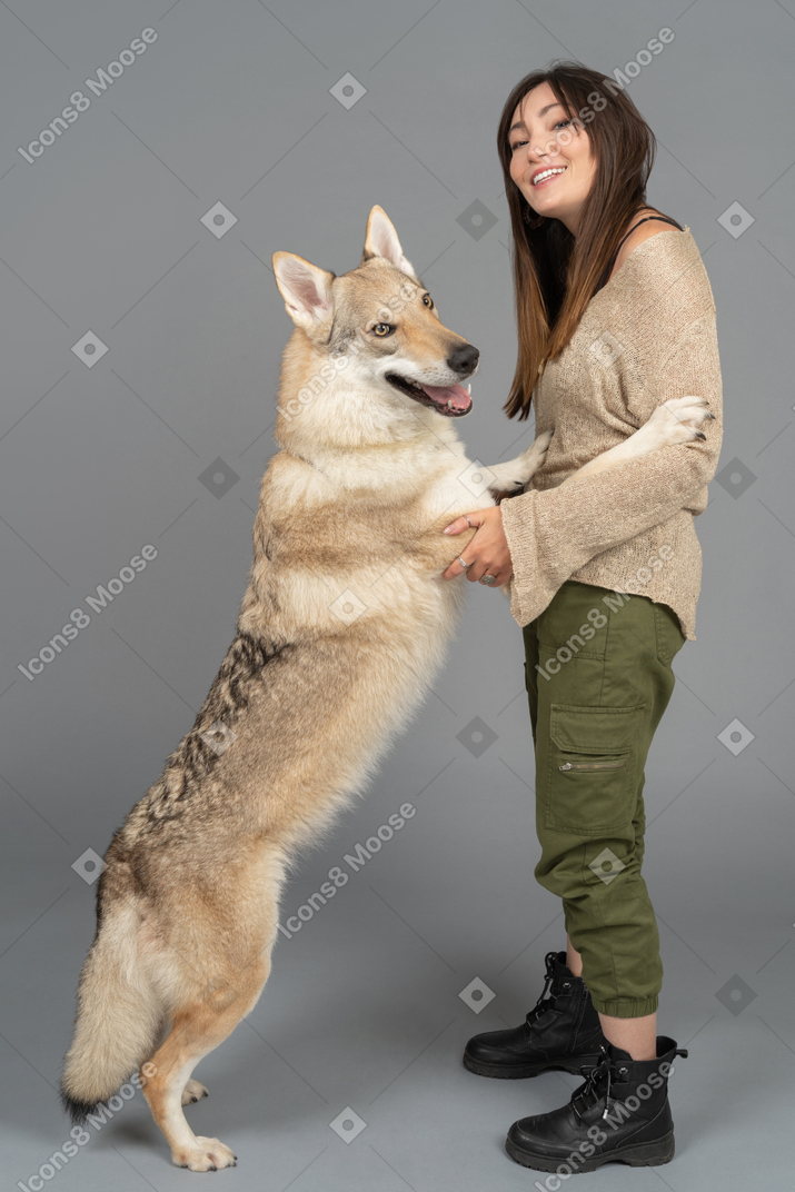 Juguetón perro de raza pura abrazando a una mujer joven