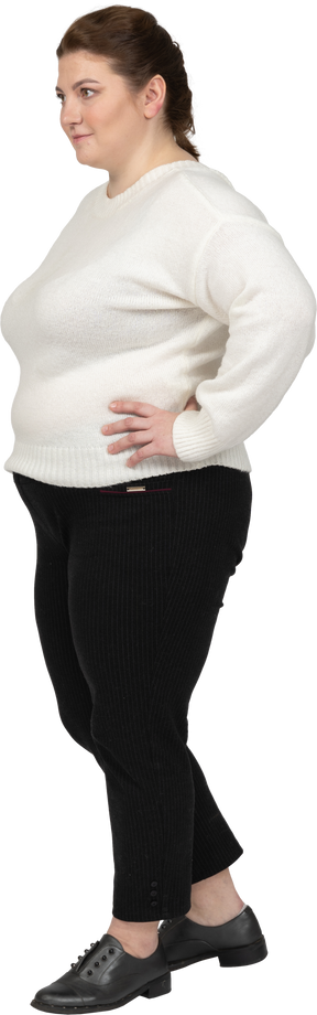 Mujer regordeta en suéter blanco posando con las manos en las caderas