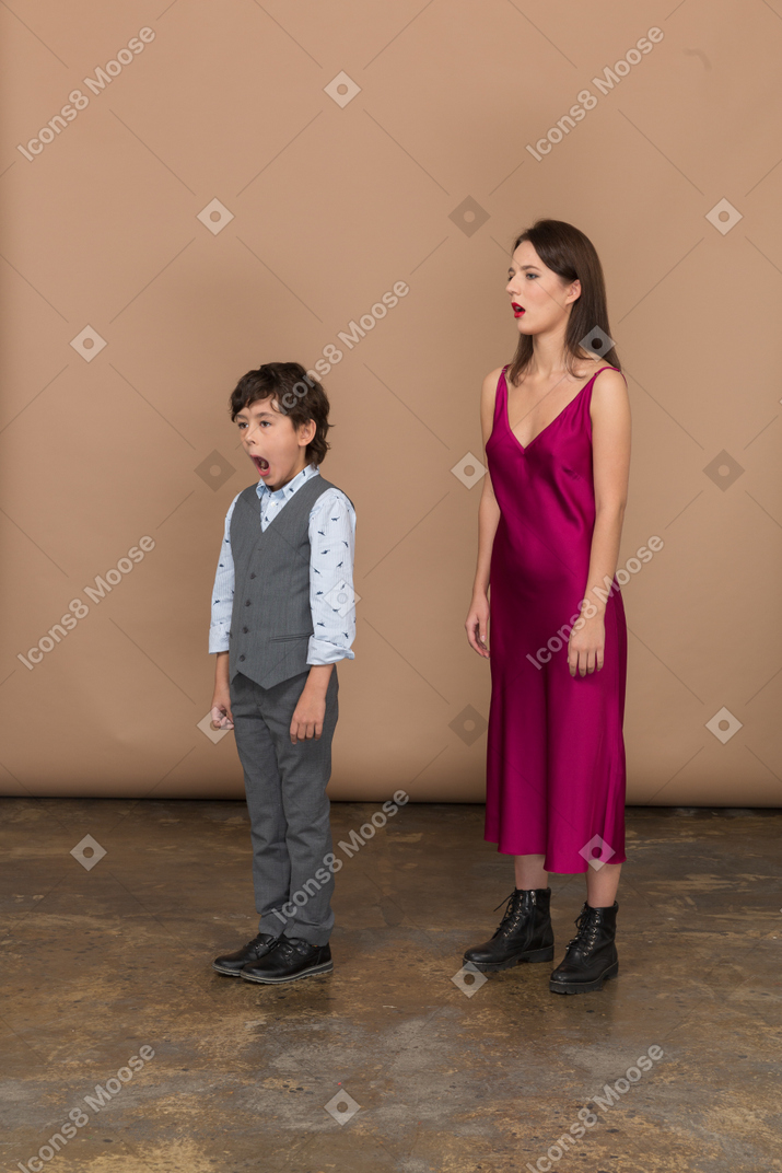 Сонная женщина в красном платье и мальчик в сером жилете костюма
