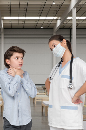 A nurse and a boy are standing in a room