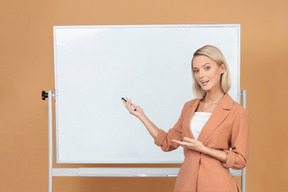 Jolie femme debout à côté d'un tableau blanc et expliquer quelque chose