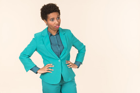 Black woman with a short haircut, wearing all blue, standing against a plain pastel background, looking emotional