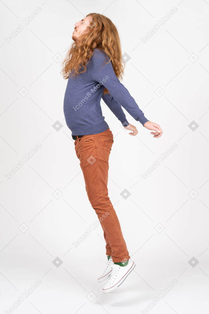 Vista laterale di un giovane in abiti casual che saltano