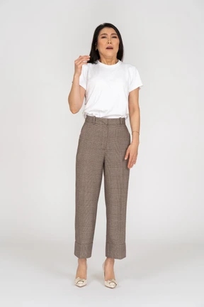 Front view of a sneezing young lady in breeches and t-shirt raising hand