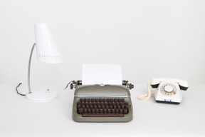 Vintage typewriter, corded phone and a table lamp