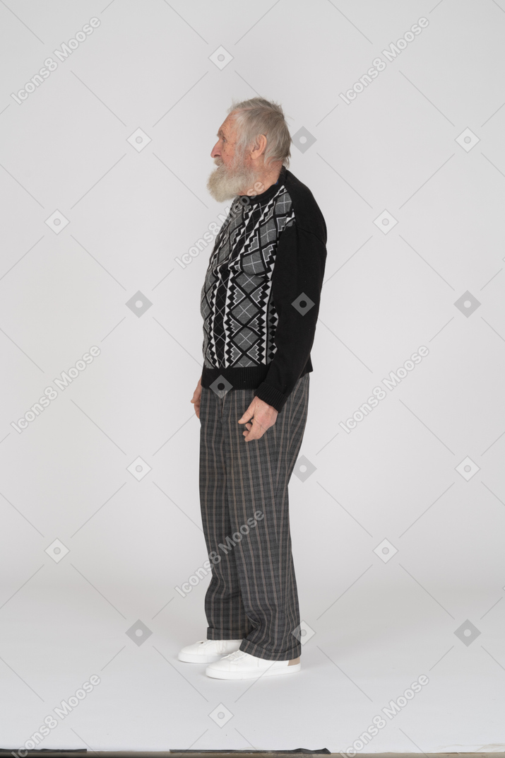 Side view of bearded old man standing with arms at side