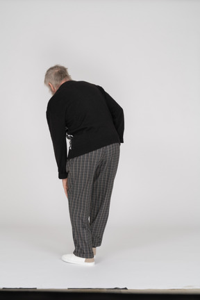 Back view of old man groaning with pain in leg