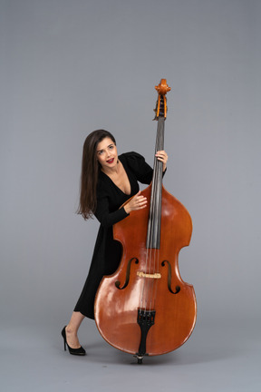 Front  view of a young woman in black dress playing the double-bass