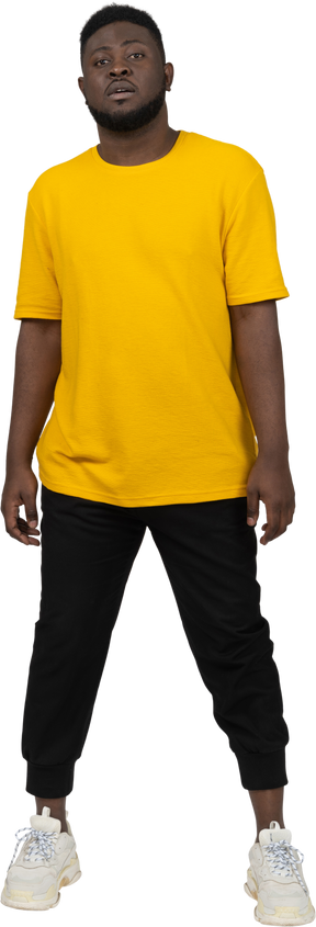 Front view of a young dark-skinned man in yellow t-shirt standing still