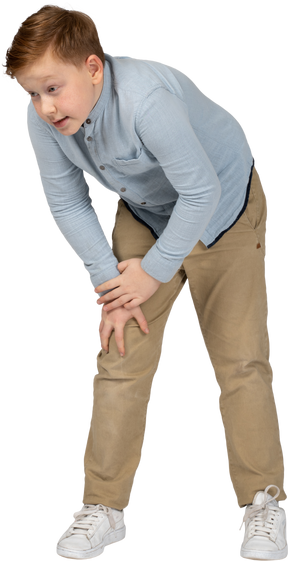 Front view of a boy bending down and touching hurting knee