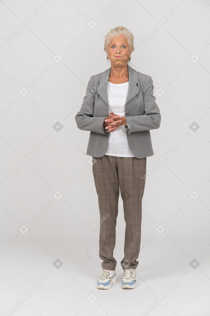 Vista frontal de una anciana en traje mirando a la cámara y haciendo muecas