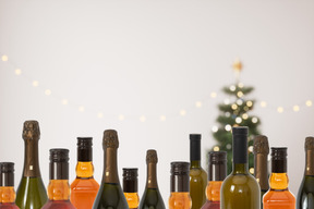 Rows of bottles of wine in front of a christmas tree