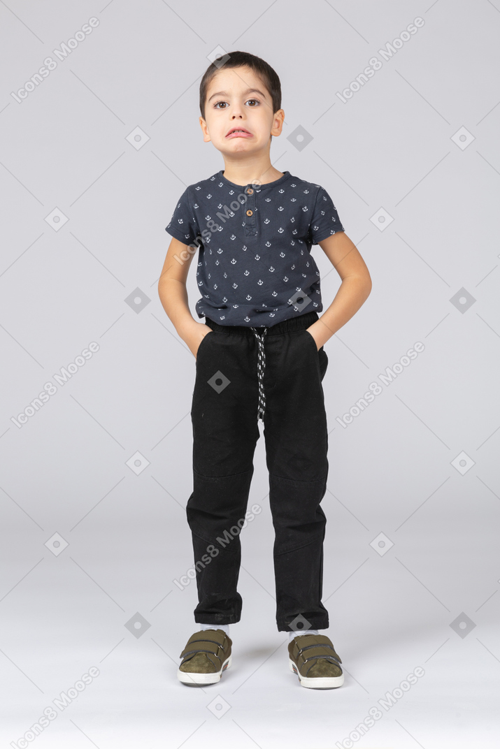Front view of a boy posing with hands in pockets and making faces