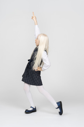 Schoolgirl pointing upwards with hand on waist
