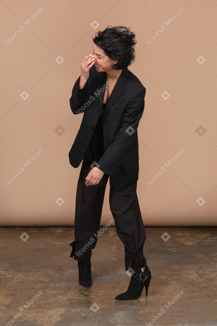 Vista frontal de uma empresária sorridente, vestindo um terno preto e tocando o nariz