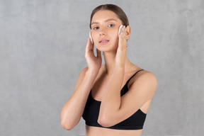 Young woman wiping her face with cotton pads