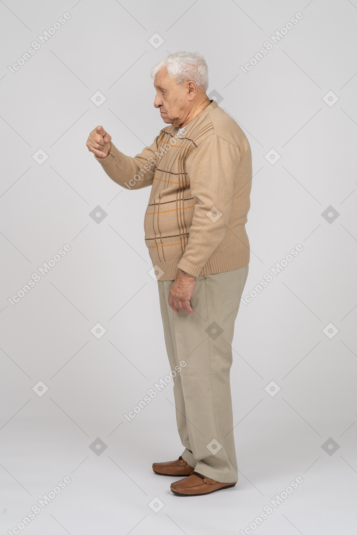 一位穿着休闲服的老人用手指指着的侧视图