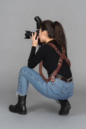Joven mujer tomando fotos mientras está sentado en las ancas