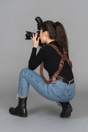 Young female taking photos while sitting on haunches